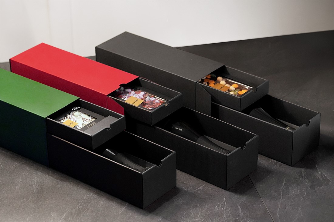 Gift boxes with drawers – black, red, and green, containing a bottle and chocolate
